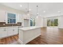 Open concept kitchen with island, white cabinets, and hardwood floors at 2269 Abbeyhill Dr # 133, Raleigh, NC 27610