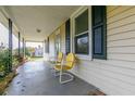 Covered porch with two yellow metal chairs and brick base at 1054 George Bason Rd, Graham, NC 27253