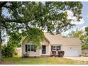Beige house with a white garage door and landscaping at 1309 S 11Th St, Lillington, NC 27546