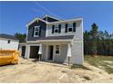 Two-story house with gray and blue siding, a two-car garage, and a partially landscaped yard at 223 Rocking Horse Ln, Sanford, NC 27332