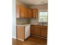 L-shaped kitchen with wood cabinets, white appliances, and laminate floors at 168 Randolph Dr, Clayton, NC 27520