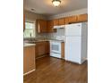 Kitchen with wood cabinets, white appliances, and laminate floors at 168 Randolph Dr, Clayton, NC 27520