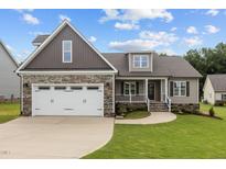 Two-story home with a stone and siding exterior, a three-car garage, and a covered porch at 75 Woodbark Cv # 10, Willow Springs, NC 27592