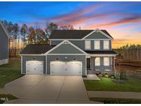 Two-story home with gray siding, two-car garage, and landscaped front yard at 305 Sutherland Dr, Franklinton, NC 27525