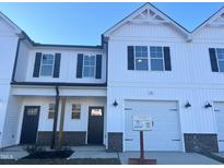 White two-story townhome with a two-car garage and landscaping at 97 Calluna Dr, Clayton, NC 27520