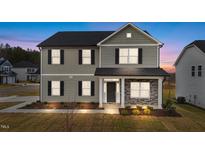 Two-story home with gray siding, stone accents, and a covered front porch at twilight at 535 Husketh Rd, Youngsville, NC 27596