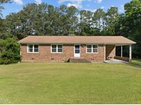 Brick ranch house with a covered porch and well-maintained lawn at 3721 Brightwood Ln, Durham, NC 27703