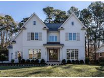 Two-story white farmhouse features double front doors, shutters, and a manicured lawn at 4800 Latimer Rd, Raleigh, NC 27609