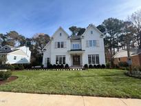 Two-story white farmhouse with a classic design and lush lawn at 4800 Latimer Rd, Raleigh, NC 27609