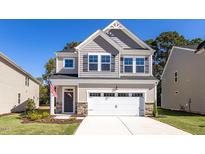 Two-story home with gray siding, white garage door, and landscaped lawn at 212 Gregory Village Dr, Lillington, NC 27546