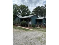 Green house with a gravel driveway and mature trees at 7253 Hunt Valley Trl, Wendell, NC 27591