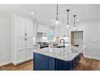 Modern kitchen with white cabinets, a large island, and stainless steel appliances at 5501 Daywood Ct, Raleigh, NC 27609