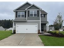 Two-story home with gray siding, white garage door, and landscaping at 815 Rhino Bnd, Oxford, NC 27565