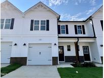 White two-story home with black accents, two-car garage, and landscaped lawn at 69 Calluna Dr, Clayton, NC 27520