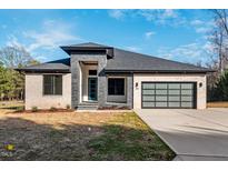 Modern ranch home with brick and stone exterior, a teal door, and glass garage door at Lot 4 Harding St, Efland, NC 27243