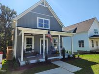 Charming gray farmhouse with a covered porch and American flag at 199 N Smith St, Clayton, NC 27520