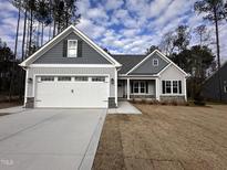 Gray and white two-story house with a three-car garage and landscaping at 153 Wilderness Trl, Smithfield, NC 27577