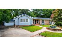 Brick and gray-sided house with a fountain, attached garage, and landscaped yard at 1320 Wagram Ct, Raleigh, NC 27615