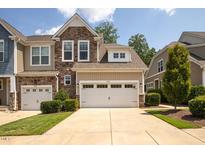 Two-story townhome with stone and siding accents, two-car garage, and landscaped front yard at 622 Chronicle Dr, Cary, NC 27513