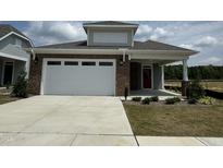 Brick home with a two-car garage and landscaping at 324 Village Walk Dr, Clayton, NC 27527