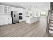 Modern kitchen with white cabinets, island, and stainless steel appliances at 1226 Helms St, Durham, NC 27713