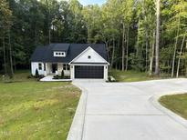 White farmhouse exterior with black garage door and landscaping at 114 Shaman Dr, Louisburg, NC 27549