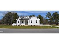 White farmhouse exterior with a landscaped lawn at 15 Bella Ln, Zebulon, NC 27597