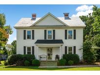 Two-story white farmhouse with black shutters, a front porch, and landscaping at 1502 Bahama Rd, Bahama, NC 27503