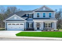 Two-story home with gray siding, stone accents, and a three-car garage at 591 Glenkirk Pl # 106, Garner, NC 27529