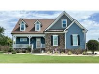 Two-story blue home with stone accents, front porch, and landscaped yard at 1337 Turner Woods Dr, Raleigh, NC 27603