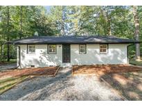 Newly renovated white house with black trim and gravel driveway at 114 Glosson Cir, Carrboro, NC 27510