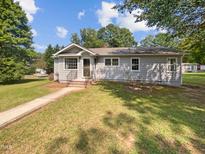 Gray house with a walkway leading to the entrance, surrounded by a well-maintained lawn at 1421 Athens Dr, Raleigh, NC 27606