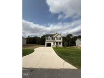 Two-story house with beige siding, black windows, and a concrete driveway at 153 Wynd Crest Way, Benson, NC 27504