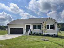 Newly built ranch home with tan siding, brown garage door and landscaped yard at 66 Tulipfield Way, Benson, NC 27504