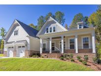 Two-story home with gray siding, brick accents, and a three-car garage at 143 Traceway N, Sanford, NC 27332