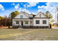 White farmhouse exterior with stone accents and a landscaped lawn at 4155 Us-421, Lillington, NC 27546