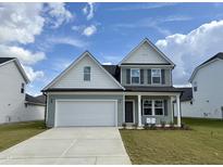 Two story home with a white and gray exterior, two car garage, and landscaping at 824 Putney Hill Rd, Zebulon, NC 27597
