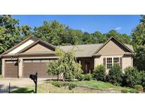 House exterior featuring a three-car garage and landscaping at 95 Crownside Dr, Four Oaks, NC 27524