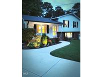 Evening view of charming ranch home with landscaped yard and walkway at 1704 Chestnut St, Apex, NC 27502