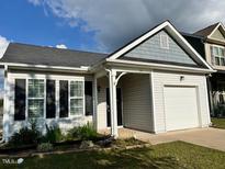 Charming one-story home with gray and white siding, a two-car garage, and landscaped yard at 24 Manito Pl, Clayton, NC 27520