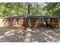 Brick ranch house with a wooden front porch and a gravel driveway at 118 W Silver Belle Dr, Zebulon, NC 27597