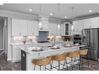 Modern kitchen with white cabinets, large island, and stainless steel appliances at 5013 Trotter Dr, Raleigh, NC 27603