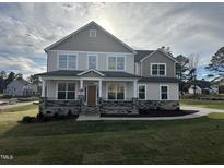 Two story house with gray siding, stone accents, and a large front yard at 23 Quail Point Cr, Clayton, NC 27520