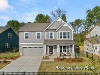 Two-story house with gray siding, a three-car garage, and landscaping at 101 Horseshoe Pl # 59P, Angier, NC 27501