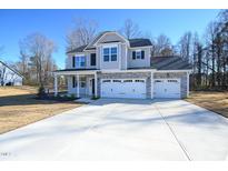 Two-story house with gray siding, stone accents, and a three-car garage at 49 Abingdon Farms Dr, Selma, NC 27576