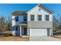 Two-story home with gray and white siding, white garage door, and landscaping at 259 Johnson Ridge Way, Four Oaks, NC 27524