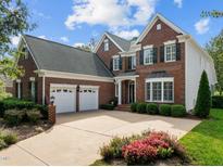 Two-story brick home with a two car garage and landscaping at 9432 Palm Bay Cir, Raleigh, NC 27617