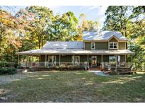 Front view of a two-story green house with a wrap-around porch at 7925 S Highway 55, Willow Springs, NC 27592