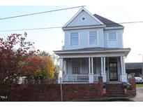 Two-story light blue house with a wrap-around porch and brick accents at 316 E South St, Raleigh, NC 27601