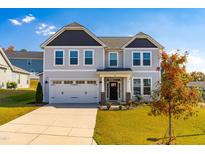 Two-story home with gray siding, a three-car garage, and a well-maintained lawn at 52 E Piston Pt, Clayton, NC 27520